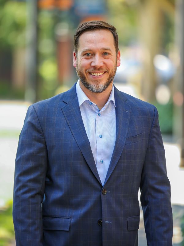 Man in blue suit smiles for a headshot 