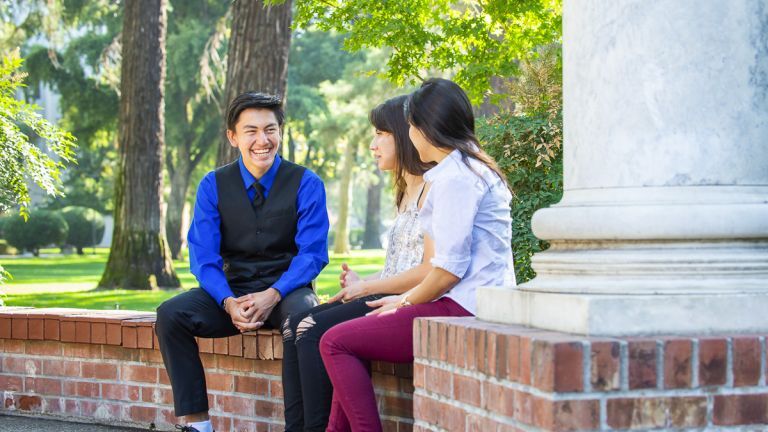 Success TRiO student sitting at columns on campus