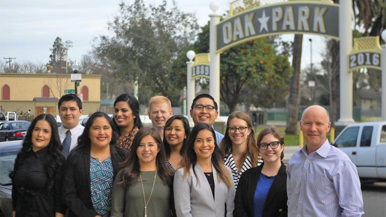 McGeorge Immigration Law Clinic students and staff attorney Blake Nordahl across the street from a park in Sacramento's Oak Park neighborhood