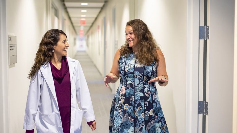 a doctor and a student talking as they walk down a hallway together