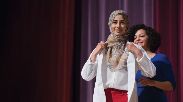 PharmD incoming student being cloaked at the White Coat Ceremony