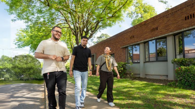 three students walk down the sidewalk together