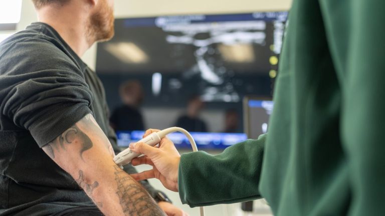 Image shows two students practicing a procedure in the lab. 