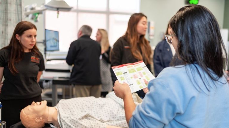 Image shows a student reviewing instructions in clinical skills lab