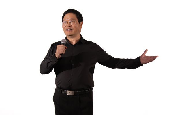 Professor Xin Guo singing into microphone.