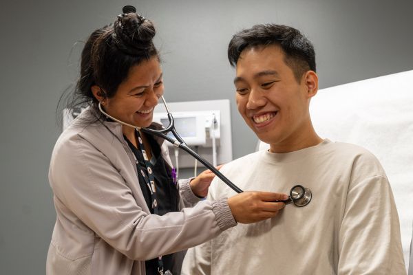 The nurse practicioner using her stethoscope on a male patient.