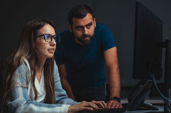 Cybersecurity student looking at computer screen with teacher