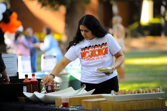 Woman in McGeorge shirts grabs food from table