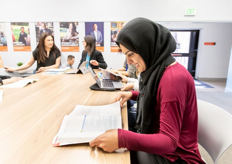 student in classroom looking at textbook