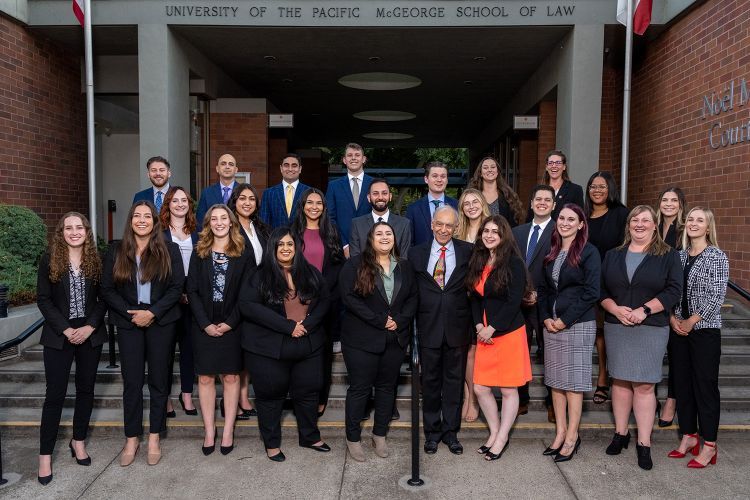 A group of people pose for a photo on the steps of a building 