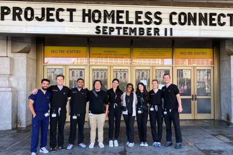 Group of student volunteers in front of Bill Graham Civic Auditorium under a marquee reading Project Homeless Connect 82