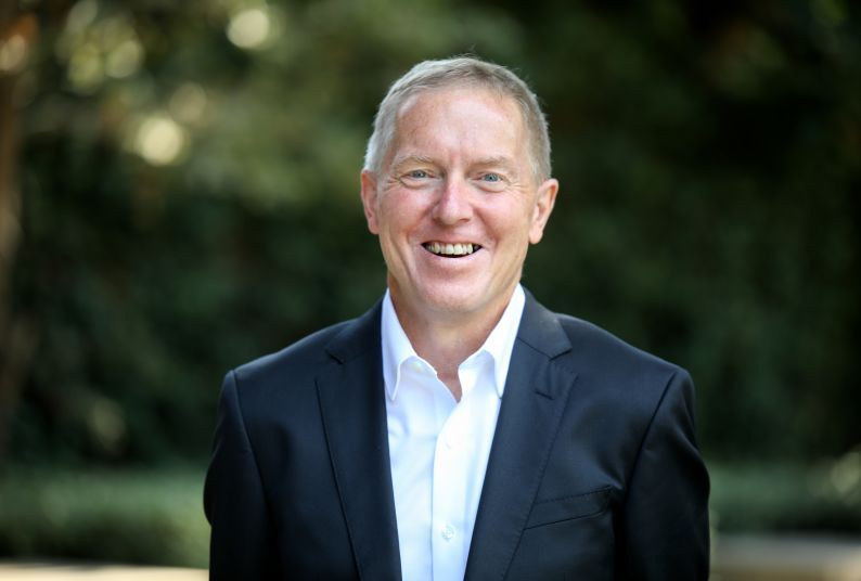 A portrait of Kevin O’Keefe in front of a green background 