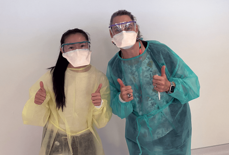 two people gowned up giving the thumbs up signal