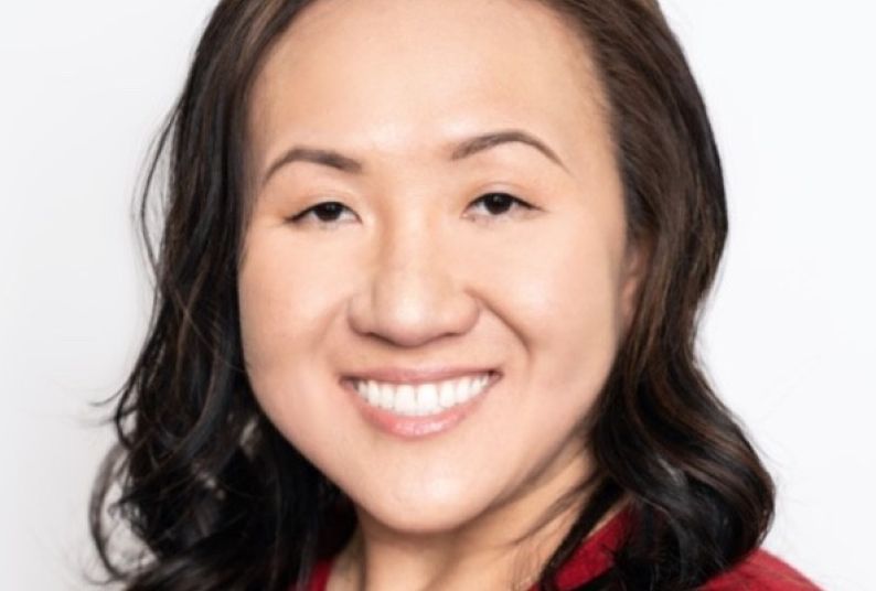 Headshot of woman with long dark hair and red top.