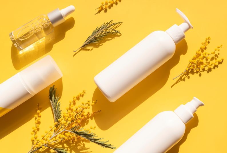 Beauty products and small plants against a yellow background