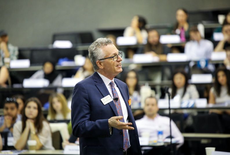 A man speaks to a room full of students