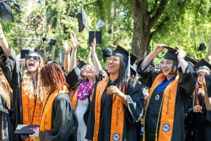 student-athletes throw their graduation caps into the air at commencement