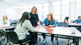 students interact with professor in classroom