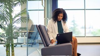 Woman typing on laptop, sitting in a chair