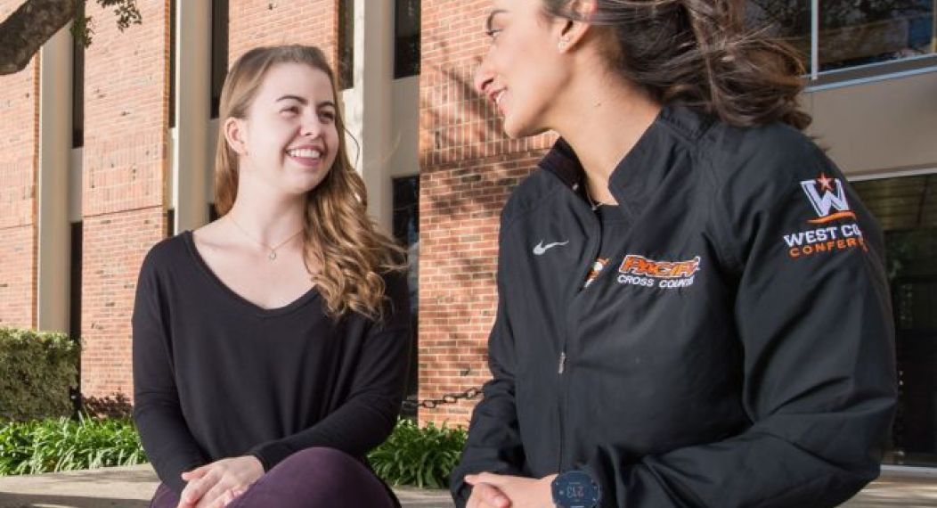 two students sitting on a ledge and talking