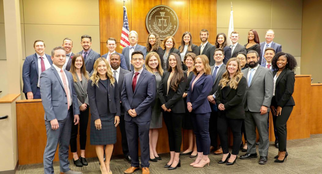 A group photo of 30 people in a courtroom.