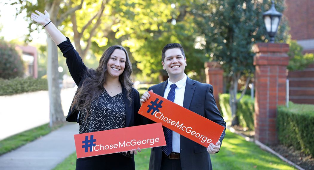 Two students holding small orange signs