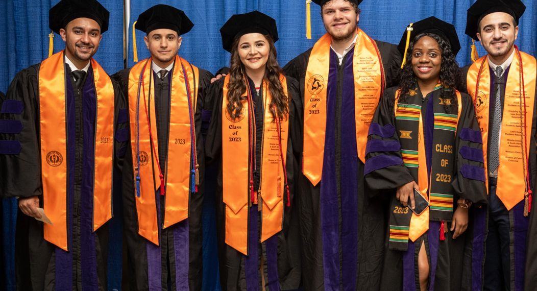 A group of six graduates wearing regalia 