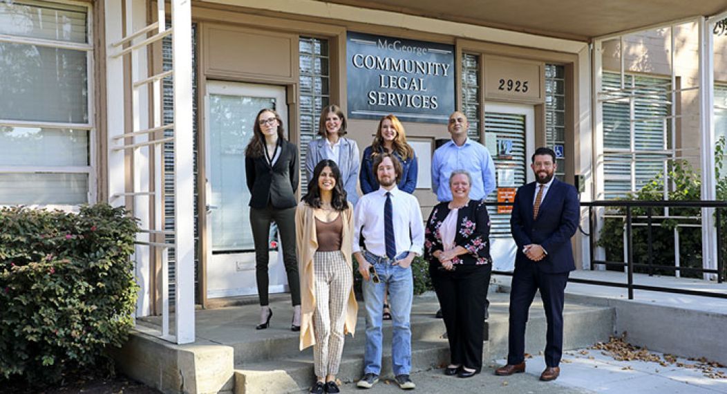 Eight people stand in front of the Community Legal Services building.