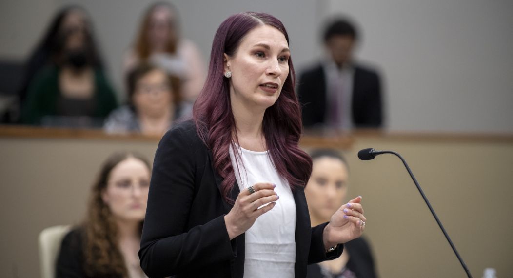 A law student stands at a podium in a courtroom.