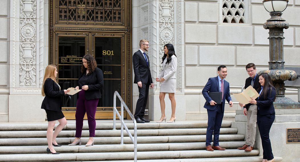 Seven students converse on the steps of a government building