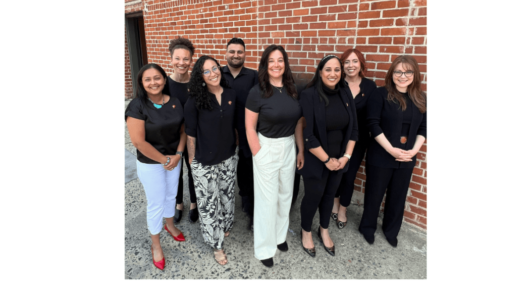 Photos shows the faculty & staff of the OT Department standing against a brick wall. 