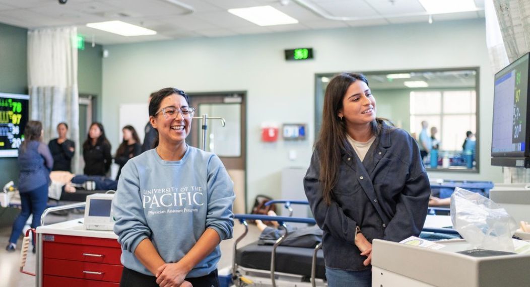 Photo shows two students standing in the lab and smiling. 