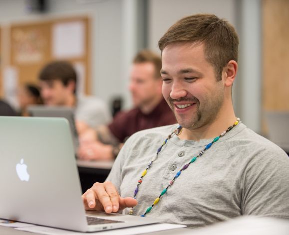 student using laptop and smiling