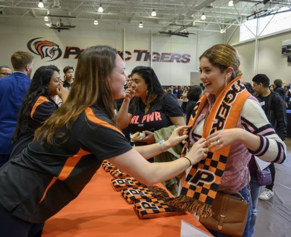 staff member giving student a Tiger scarf