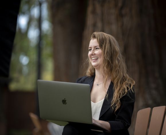 student with laptop sitting on chair outside