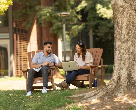 Two people sitting under a tree