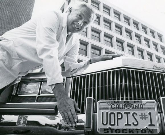 man with car with license plate that reads "uopis#1"