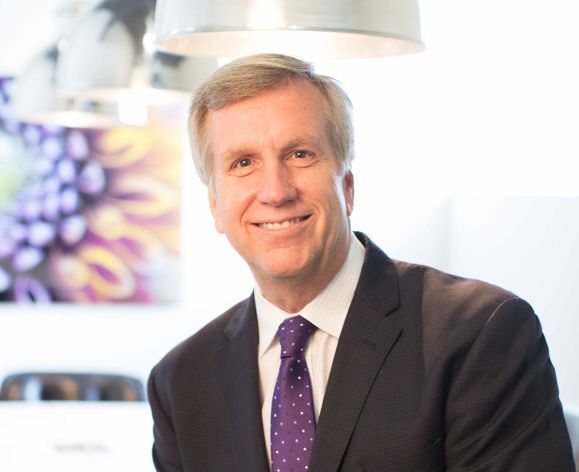 A man wearing a suit smiles for a photo indoors