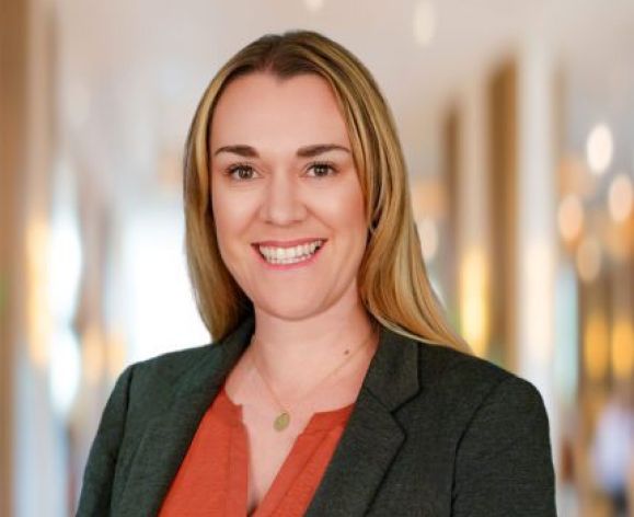 A woman wearing a suit smiles for a photo indoors